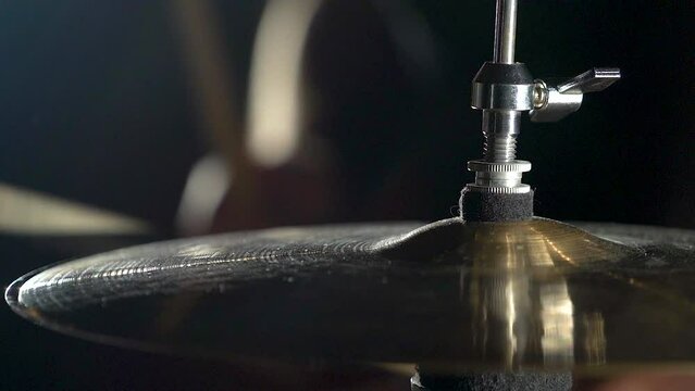 Close-up view of cymbals in drum kit and man musician playing with drumsticks.