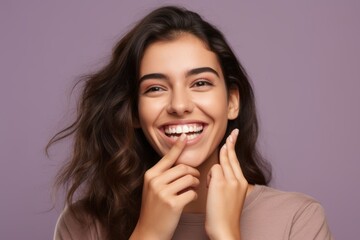 Fototapeta premium Headshot portrait photography of a grinning girl in her 20s placing the hand over the mouth in a laughter gesture against a soft lavender background. With generative AI technology