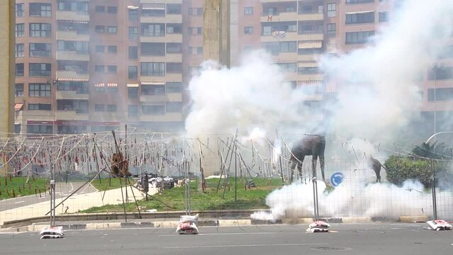 Explosion de enormes petardos de una Traca , corre fuego , mascletá, petardos , fuego artificiales en la calle llena de humo