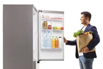 Man with a grocery bag opening a fridge door