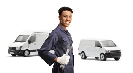 African american auto mechanic holding a wrench and standing in front of two vans