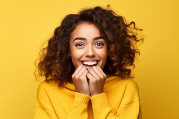 Medium shot portrait photography of a grinning girl in her 20s covering one's mouth against a pastel yellow background. With generative AI technology