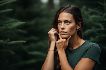 Photography in the style of pensive portraiture of a satisfied girl in her 30s making a i'm listening gesture with the hand on the ear against a forest green background. With generative AI technology