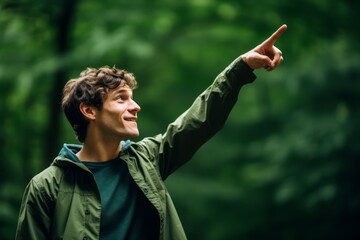Fototapeta premium Close-up portrait photography of a satisfied boy in his 30s pointing up against a forest green background. With generative AI technology