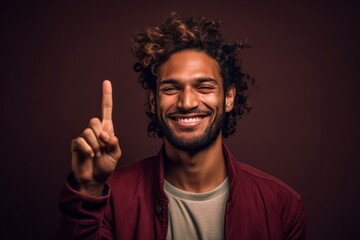 Headshot portrait photography of a satisfied boy in his 30s making a peace and love gesture with the fingers against a rich maroon background. With generative AI technology