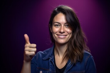 Close-up portrait photography of a satisfied girl in her 30s making an ok gesture with the fingers against a deep purple background. With generative AI technology
