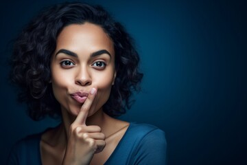 Close-up portrait photography of a happy girl in her 30s making a silence gesture by putting the index finger on the lips against a deep sea-blue background. With generative AI technology