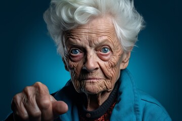 Headshot portrait photography of a tender old woman pointing at oneself against a deep sea-blue background. With generative AI technology