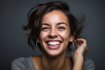 Close-up portrait photography of a grinning girl in her 30s covering one's ears against a metallic...