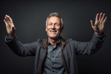 Medium shot portrait photography of a glad mature man extending arms to one side in a gesture of freedom against a metallic silver background. With generative AI technology