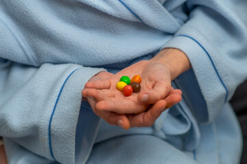 Multi-colored candies on a female palm. Small amount, diet, restriction in sweets concept.