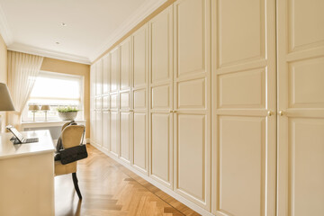 a home office with white cabinetry and wood flooring in the room is lit by a large window that looks out onto the