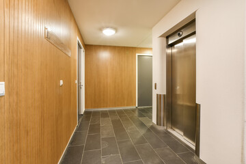 a long hallway with wood walls and tile flooring on both sides, leading to an elevator in the center