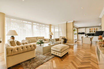 a living room with wood flooring and white sofas in the center of the room is an open kitchen