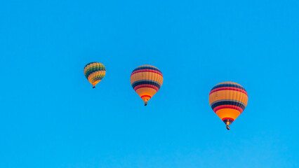 Fototapeta na wymiar Cappadocia Turkey. Hot air balloons flying over fairy chimneys at sunrise in Cappadocia. Travel to Turkey. Touristic landmarks of Turkiye. Selective focus included.