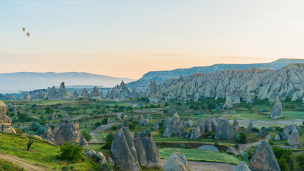 Fototapeta premium Cappadocia Turkey. Hot air balloons flying over fairy chimneys at sunrise in Cappadocia. Travel to Turkey. Touristic landmarks of Turkiye. Selective focus included.