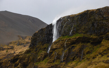 Fototapeta na wymiar Large waterfall in Iceland. The water is blown away by the wind