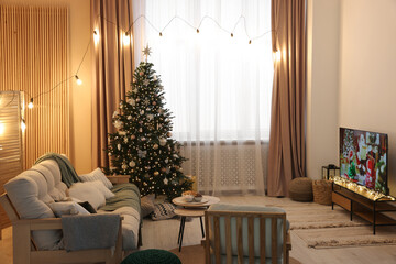 Wide TV set, furniture and Christmas tree in stylish room