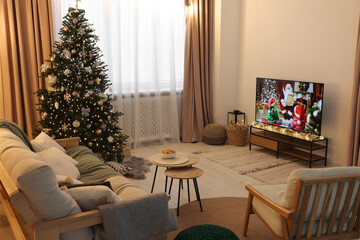 Wide TV set, furniture and Christmas tree in stylish room