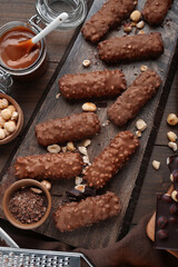 Tasty chocolate bars with caramel and nuts on wooden table, flat lay