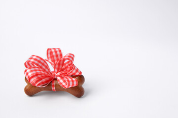 Bone shaped dog cookie with red bow on white background, space for text