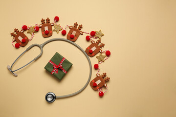 Greeting card for doctor with stethoscope, gift box and Christmas decor on beige background, flat lay. Space for text © New Africa