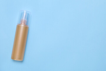 Bottle of face cleansing product on light blue background, top view. Space for text