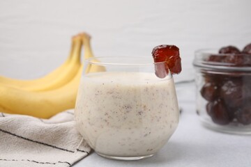 Glass of delicious date smoothie on white table, closeup