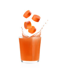 Splashing freshly made carrot juice on white background. Cut carrot falling into glass © New Africa
