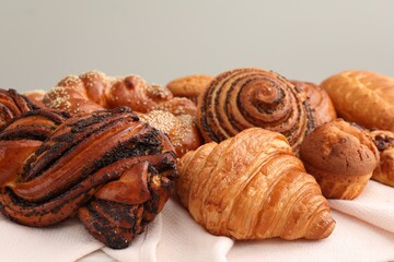 Different tasty freshly baked pastries on white tablecloth, closeup