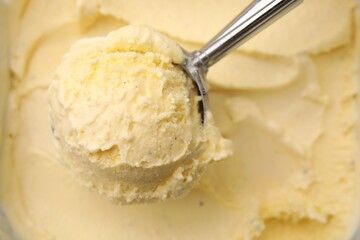 Taking scoop of vanilla ice cream from container, closeup