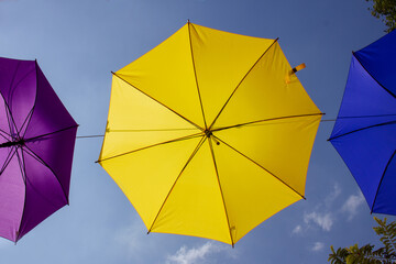 Guarda-chuvas coloridos com fundo azul céu, na rua