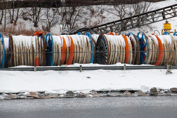 Bulk sub-sea industrial glass fiber optic cable on a metal spool on ship stands. The data line is...