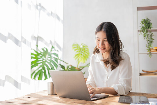 Asian Businesswoman Sitting At Desk With Laptop And Tablet Calculating Financial Graph Showing Results About Investment Growing Successful Business