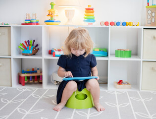 Toddler girl sitting on a potty with the tablet. Potty training. Toilet training