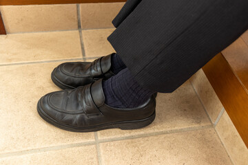 黒のビジネスシューズを履いた男性の足
