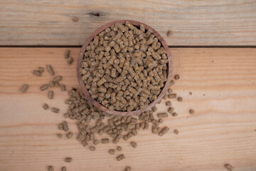 selective focus on brown chicken pellets on a wooden bowl, pellets are chicken feed made from corn and vegetables mixed with water