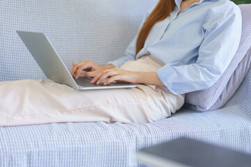 Naklejka premium Home office concept, Businesswoman lying on the couch to typing marketing plan report on laptop
