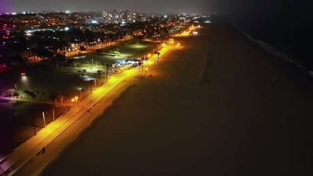Aerial Flying Over Santa Monica Beach At Night With Cycle Path Lit By Yellow Lights