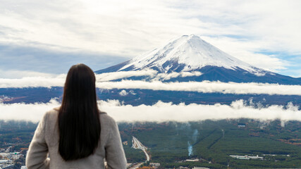 Happy Asian woman enjoy outdoor lifestyle travel Japan on autumn holiday vacation. Attractive girl tourist travel lake Kawaguchi and looking beautiful nature of Mt.Fuji covered in snow in winter day