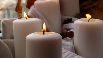 Thanksgiving and Hello Fall Halloween concept Celebrating autumn holidays at cozy home on the windowsill Hygge aesthetic atmosphere Autumn leaves, spices and candle on knitted white sweater in warm