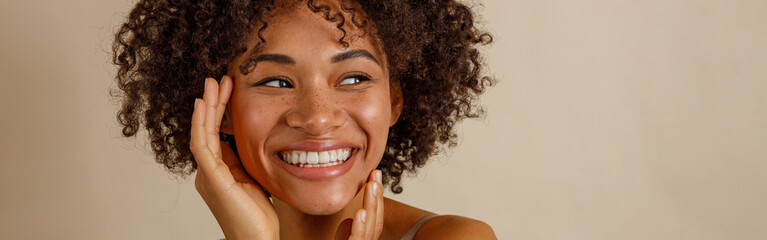 Attractive multiracial woman posing at camera over beige background