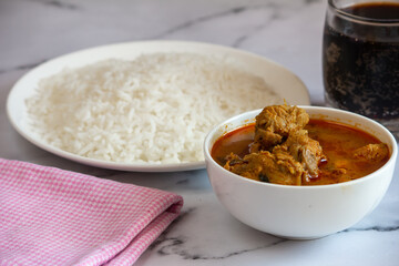 Chicken curry with rice combo with a cola drink. Spicy chicken gravy with cooked white rice.