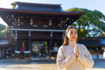 Young Asian woman praying in traditional Meiji Jingu Shrine in Tokyo city, Japan. Attractive girl...