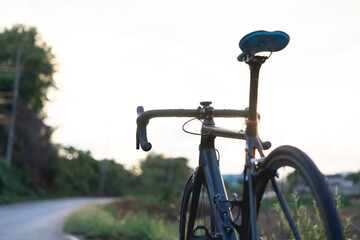 Fototapeta na wymiar Road bike parked on a beautiful road sunset, warm light with copy space. 