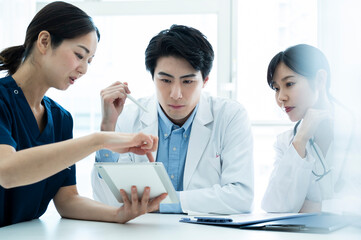 Doctors having a meeting while looking at electronic tablets and materials