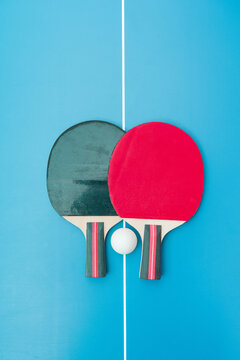 Two table tennis or ping pong rackets and balls on a blue table