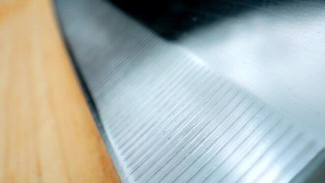 In a mesmerizing macro video, a razor-sharp chef's knife, with its intricate Damascus steel pattern, elegantly glides across a weathered wooden chopping board, revealing the precision of each cut.
