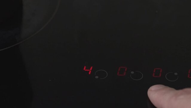 hands of person turning on touch panel of electric stove
