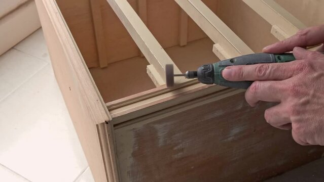 hands of carpenter man sanding furniture with a circular electric machine, close up
